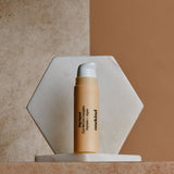 A Pep Squad Eye Revive Complex in a light tan tube with a white pump top stands against a pale brown background.