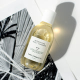 Detoxifying Daily Cleanser  bottle with gold liquid on top of black and white palm photograph