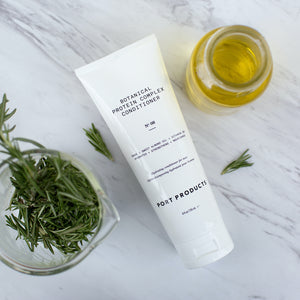 Port Products Botanical Protein Complex Conditioner white tube on marble surface with rosemary and oils