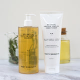 Port Products Botanical Protein Complex Shampoo and conditioner with beaker of rosemary and jar of yellow oil behind them