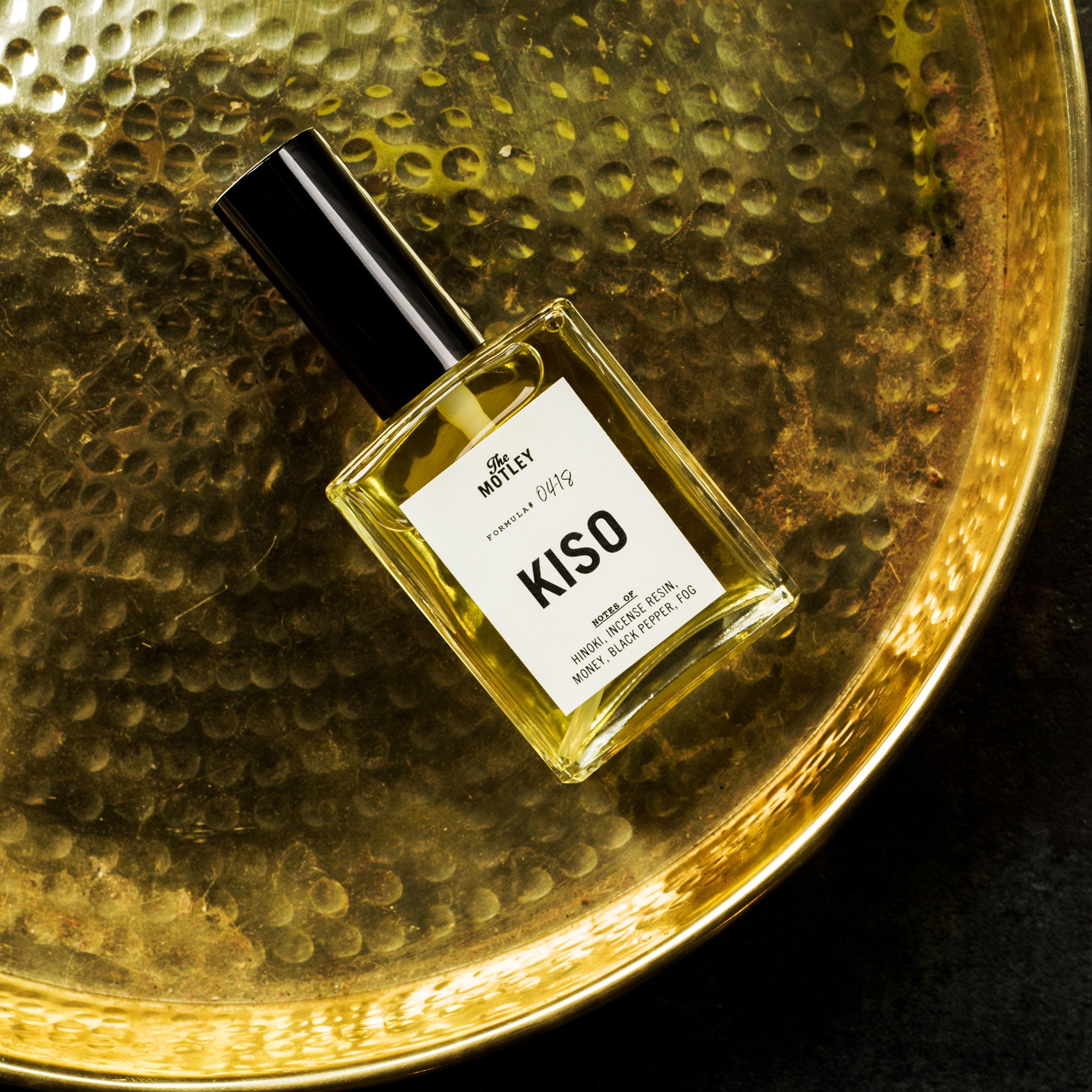 The Motley Kiso Fragrance in a glass bottle and a black pump cap rests on a gold platter.